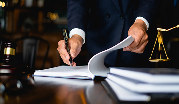 Lawyer signing legal documents at a desk with a gavel and justice scales, to symbolize a case about noncontrolling interests
