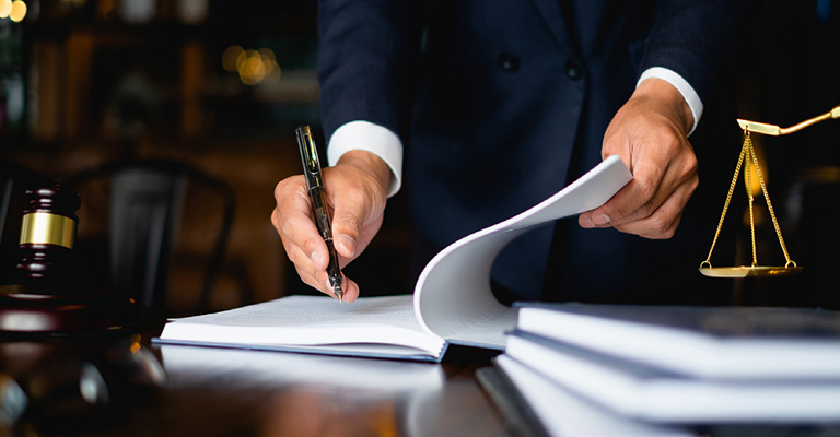 Lawyer signing legal documents at a desk with a gavel and justice scales, to symbolize a case about noncontrolling interests