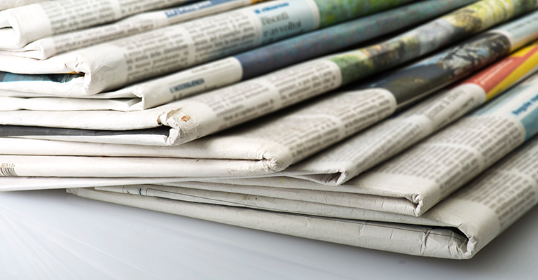 Stack of folded newspapers with visible headlines and images, to symbolize news of promotions