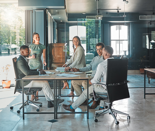 Three men sitting around table, two women standing at table