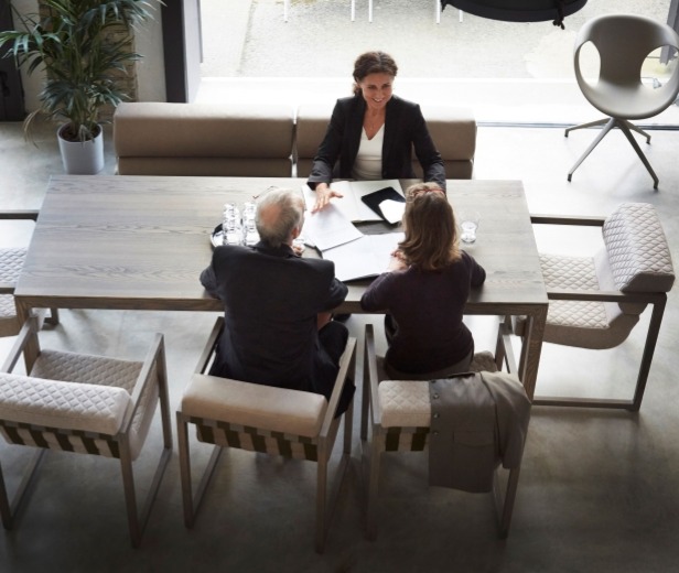 A woman sitting across a table from a man and woman, suggesting estate planning and building a trust